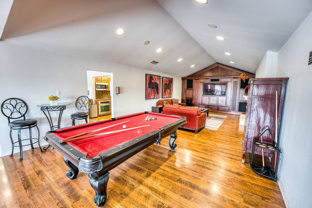 a game room with a red pool table and a red couch at Juniper Springs Apartments, Austin, TX